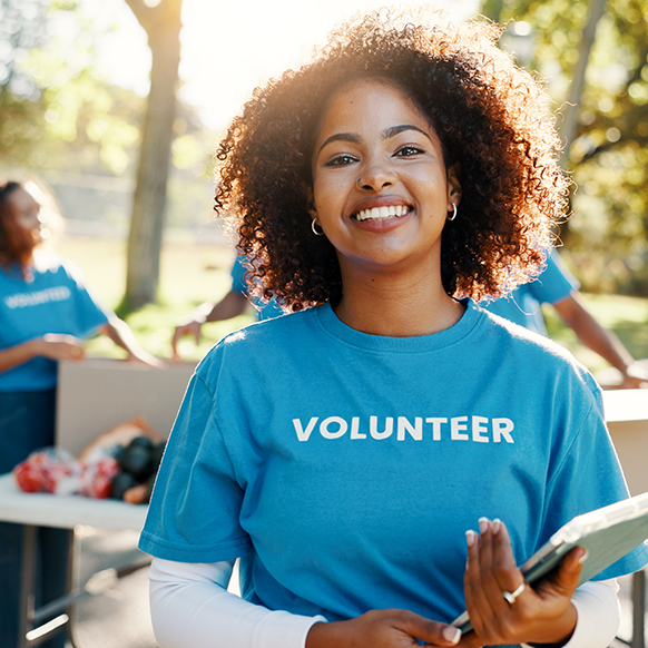 Young African American woman smiling at camera as she volunteers with group