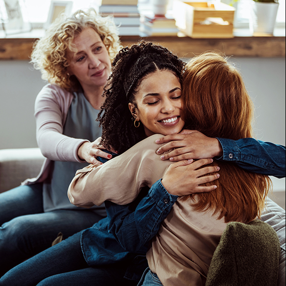 Two women hugging in a mental health treatment support group