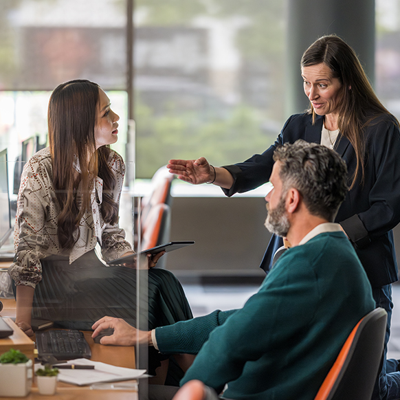 Three underwriters having a discussion around person's workstation