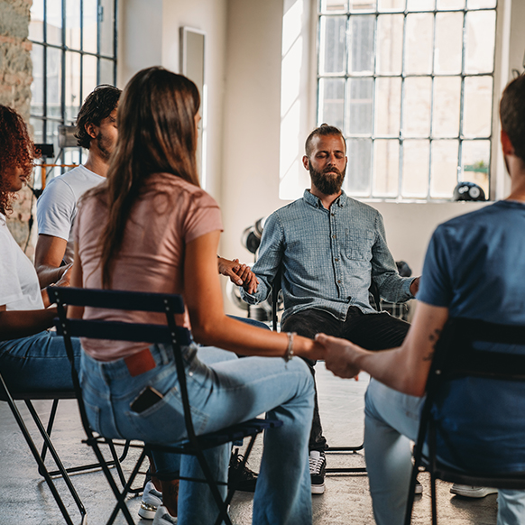 Mental health support group in circle holding hands