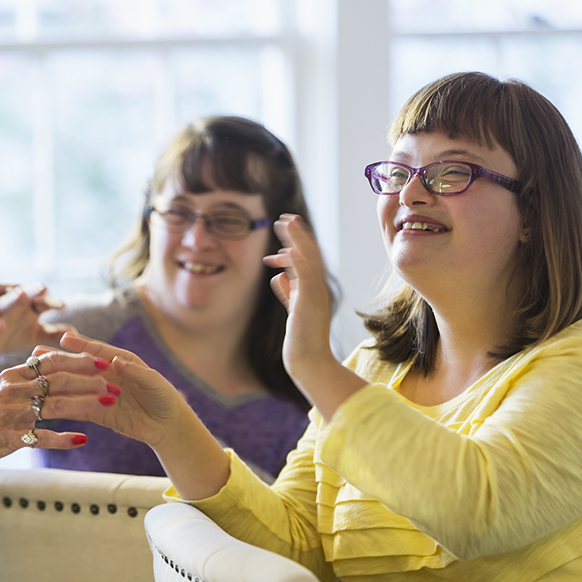 Two special needs girls smiling and enjoying their teacher's interaction