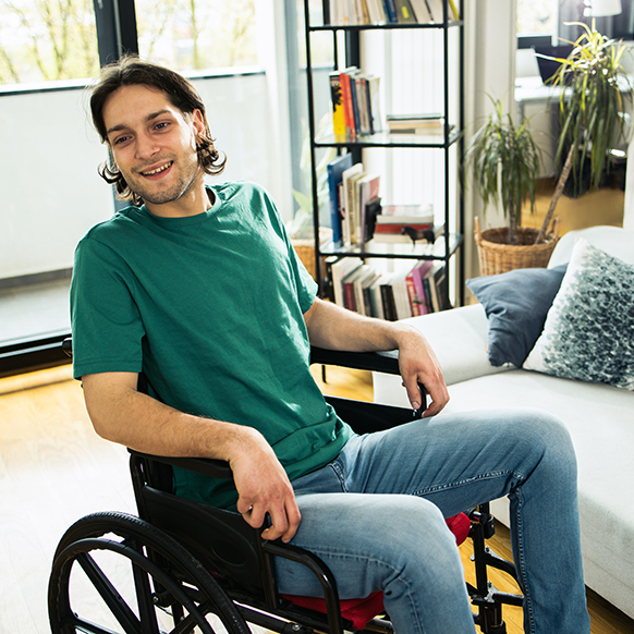 Young man in wheelchair sitting in a room at a home for disabilities