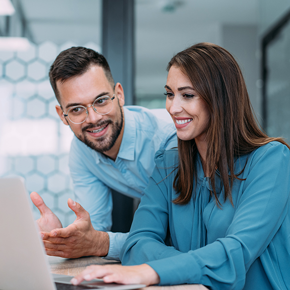 Businessman and woman closely discussing project while looking at a laptop