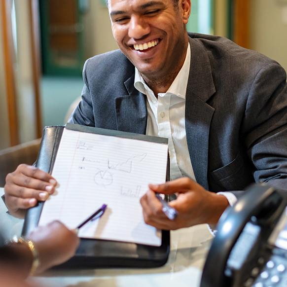 Agent explaining risk savings to human services client in office