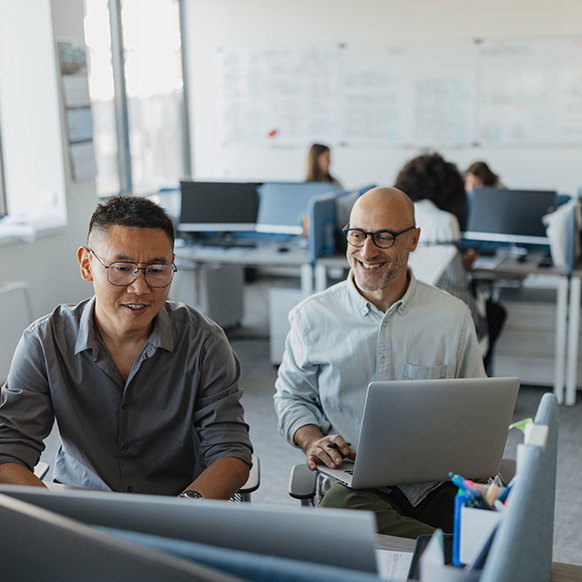 Two IT professionals collaborating and reviewing what is on the computer monitor