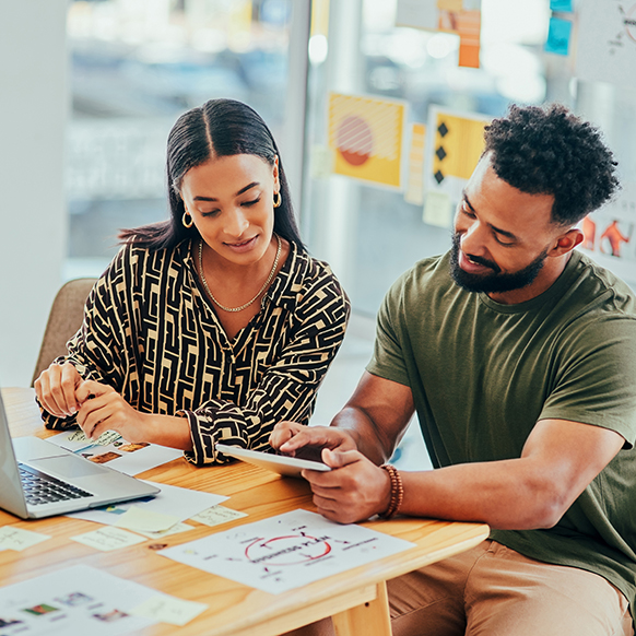 Professional young woman and man looking over marketing material at office table.