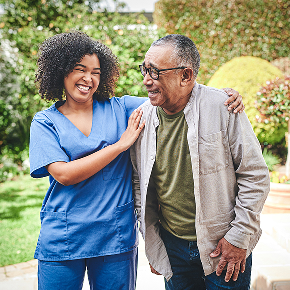 African American caregiver with elderly man walking and talking