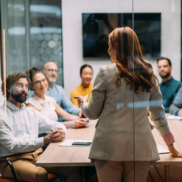 Human Resource leader standing in front of team in conference room discussing business objectives