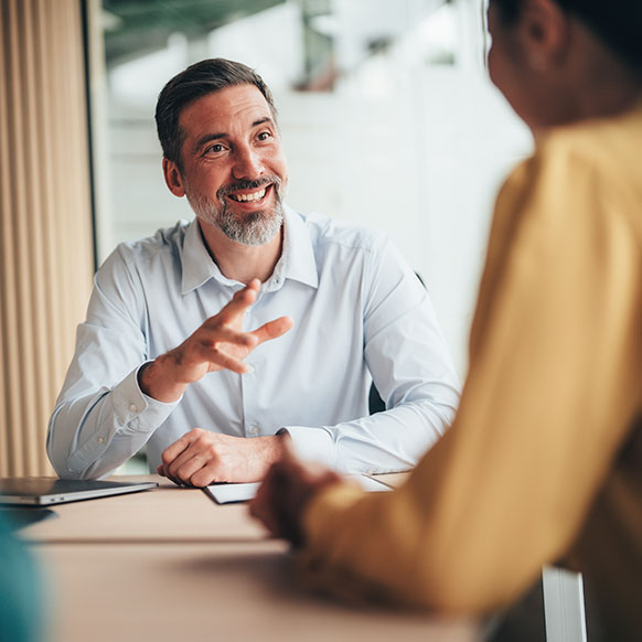 Two professionals sitting at office conference table discussion talent needs